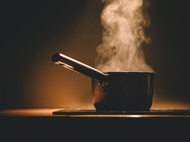 Une casserole fume sur une table de cuisson.