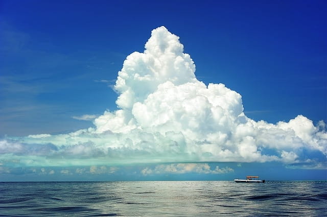 Un bateau sur une mer calme, sur fond de ciel bleu et de nuages blancs.