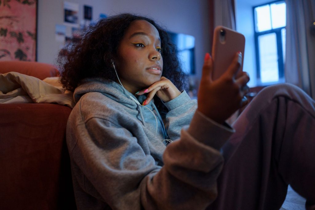Adolescente concentree sur son telephone, casque sur les oreilles