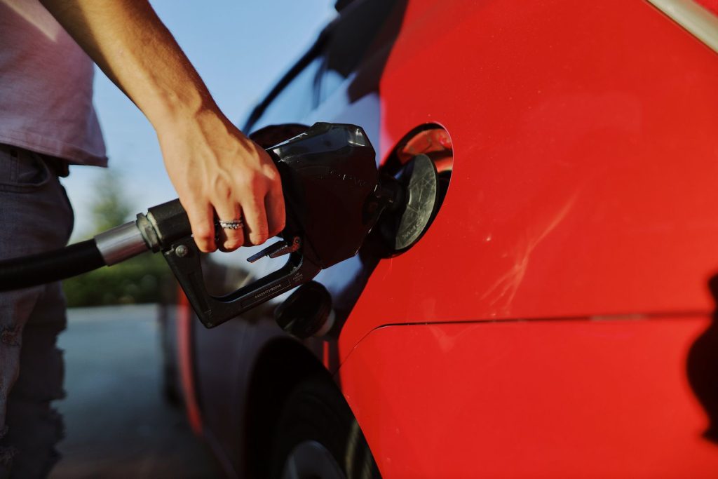Automobiliste faisant le plein de sa voiture rouge en station-service
