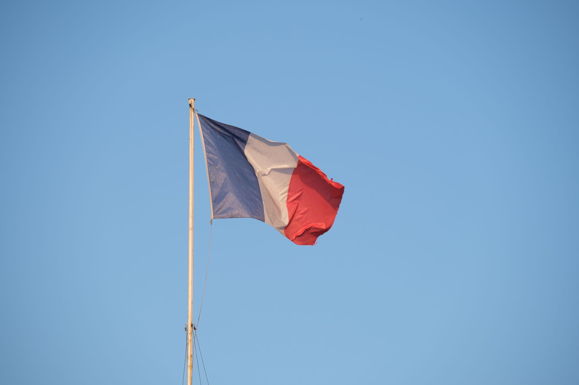 Le drapeau francais flotte devant un ciel bleu